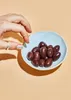 A hand is reaching for a small bowl of olives. Produktbild-Vorschau