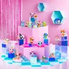 A collection of small, colorful animal figurines displayed on pink tiered platforms against a pink backdrop with shimmering pink curtains. Náhled obrázku produktu