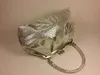 A silver clutch purse with a floral pattern is displayed on a light gray background. Podgląd zdjęcia produktu