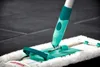 A close-up of a mop head and handle on a tiled floor. Produktbild-Vorschau