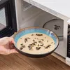 Eine gefüllte Schale wird vor die geöffnete Mikrowelle gehalten. Náhled obrázku produktu