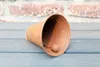 A rusty bell lies on a wooden surface in front of a brick wall. Anteprima dell’immagine prodotto