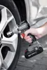 A person is using a cordless impact wrench to tighten a lug nut on a car wheel. Produktbild-Vorschau
