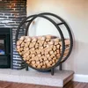 A round metal firewood rack filled with logs next to a fireplace. Náhľad obrázku produktu