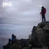 Two hikers on a rocky mountain peak under a cloudy sky. One hiker is standing and looking out, while the other is sitting and looking down. Náhled obrázku produktu