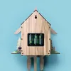 The back of a wooden cuckoo clock is shown against a light blue background. The battery compartment with three batteries is visible. Voir les images du produit