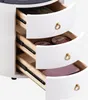 Close-up view of the drawers of a white nightstand, showing the interior and some items stored within. Voir les images du produit