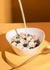 Milk being poured into a bowl of cereal with bananas and blueberries. Produktbild-Vorschau