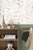 A nursery or child's room setting with a shelf displaying toys and blankets, and clothing hanging on a wall. Podgląd zdjęcia produktu