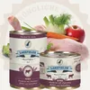 Two cans of dog food are displayed in front of a collection of fresh ingredients including chicken, carrots, fennel, broccoli, and an apple. Produktbild-Vorschau