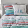 A close-up view of bedding with a nautical theme, featuring pillows and a duvet cover with sailboat and stripe patterns. Produktbild-Vorschau