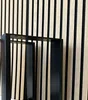 Two black metal table legs are shown in front of a slatted wooden wall. Náhľad obrázku produktu