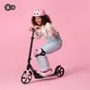 A young girl is riding a scooter and wearing protective gear. Produktbild-Vorschau