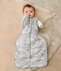 A baby is lying on a rug, wearing a sleep sack. Produktbild-Vorschau