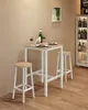 A bar table and two stools set with two plates of food, wine glasses, and a bottle of wine on the table, in front of a wall with a framed picture. A cabinet filled with bottles is to the right. Náhled obrázku produktu