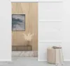 A sliding door is shown in a room setting with a picture on the wall and a basket of laundry. Náhled obrázku produktu