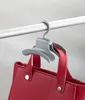 A gray handbag hanger is shown hanging from a closet rod, holding a red handbag. Produktbild-Vorschau