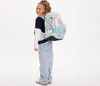 A young girl wearing a backpack stands against a white background. Podgląd zdjęcia produktu