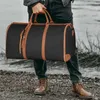 A person holding a black and brown duffel bag outdoors. Produktbild-Vorschau