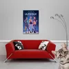 A red sofa with two pillows in front of a wall with a poster and a floor lamp. Anteprima dell’immagine prodotto