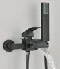 A black waterfall faucet with a handheld showerhead attached, mounted on a light gray wall. Water is flowing from the faucet. Náhled obrázku produktu