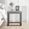 A nesting set of square side tables with a marble-look top and black metal legs, placed next to a bed. Produktbild-Vorschau