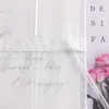 A close-up of a white fabric with handwritten text and a pink rose bouquet. Produktbild-Vorschau