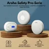 Three Aroha Safety Pro smoke and carbon monoxide detectors are displayed on wooden stands against a blue background. Below the detectors are three icons with text describing features. Produktbild-Vorschau