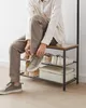 A person is sitting on a shoe rack and tying their shoes. Náhled obrázku produktu