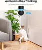 A security camera is shown above a cat, with a plant and furniture in the foreground, and a door in the background. Text overlays indicate the camera's features. Produktbild-Vorschau