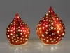 Two red decorative tear-drop shaped lanterns with star cutouts, lit from within, are displayed on a light-colored surface against a gray background. Produktbild-Vorschau