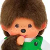 Close-up of a Monchhichi doll wearing a green frog-themed overall. Náhled obrázku produktu