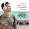 A man wearing headphones and holding a phone, with a train station in the background. Podgląd zdjęcia produktu