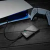 A gaming console, controller, and external SSD are arranged on a wooden surface. Voir les images du produit