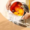 Hands washing fruit in a colander in a sink. Produktbild-Vorschau