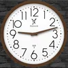 A wall clock with a wooden frame and a white face, showing the time. Voir les images du produit
