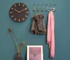 A wall with a clock, coat rack with a jacket and scarf, and framed artwork. Náhled obrázku produktu
