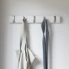 A white wall with a white coat rack holding a tote bag and a tie. Podgląd zdjęcia produktu