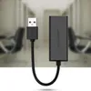 A black USB to Ethernet adapter with its cable is shown against a blurred office background. Voir les images du produit
