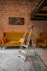 A step ladder is placed on a rug in a living room with a sofa and armchair. Anteprima dell’immagine prodotto