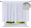 A white sheer curtain hanging over a window with a view of greenery outside. Produktbild-Vorschau