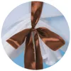 A close-up view of a brown ribbon tied into a bow around white fabric. Produktbild-Vorschau