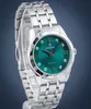A silver Festina watch with a green dial is displayed on a stand against a blue and gray background. Podgląd zdjęcia produktu