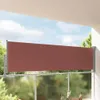 A retractable side awning on a balcony, with trees and sky in the background. Anteprima dell’immagine prodotto