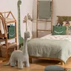 A child's bedroom with dinosaur-themed decor, including a plush dinosaur toy, a height chart, and bedding. Produktbild-Vorschau