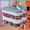 A person is holding a two-tiered storage container filled with colorful building blocks. Produktbild-Vorschau