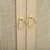 A close-up view of two round, gold-colored drawer pulls on a light wood cabinet with woven rattan panels. Podgląd zdjęcia produktu