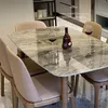 A dining table with chairs, set with wine glasses and a bottle of liquor. Produktbild-Vorschau