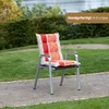 A garden chair with a striped cushion is placed on a gravel path in a garden setting. Produktbild-Vorschau