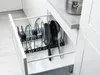 An open kitchen drawer containing a rack for pots and pans, with several lids and pans stored within. Anteprima dell’immagine prodotto
